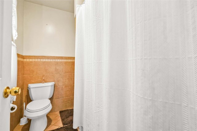 bathroom featuring tile patterned flooring, toilet, and tile walls