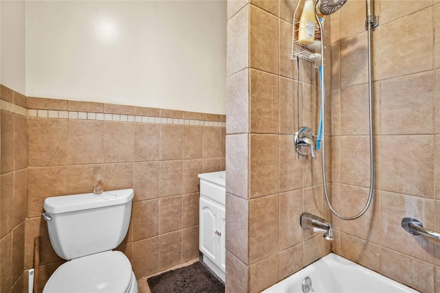 full bathroom featuring vanity, toilet, tiled shower / bath, and tile walls