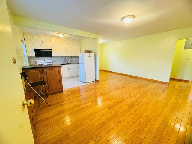 kitchen with light wood-type flooring, white appliances, and tasteful backsplash