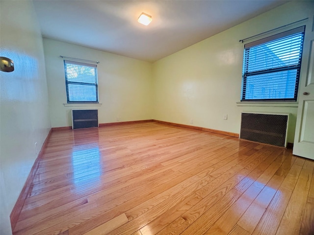 spare room with radiator heating unit and light wood-type flooring