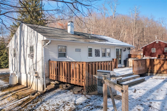 snow covered rear of property with a deck