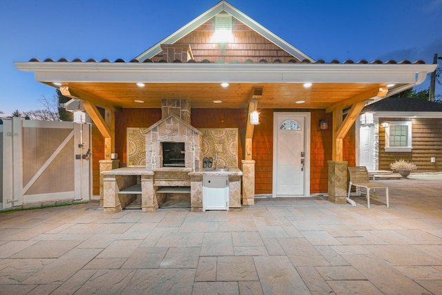 patio terrace at dusk with an outdoor stone fireplace