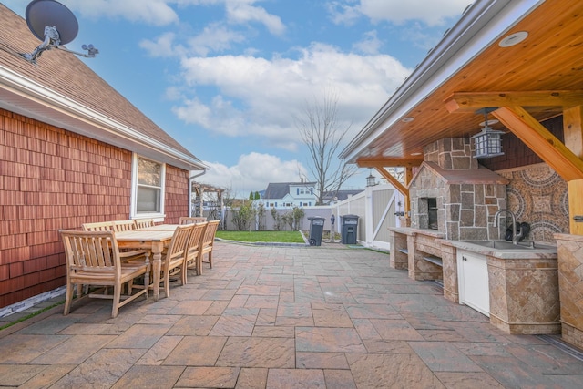 view of patio / terrace featuring sink and an outdoor stone fireplace