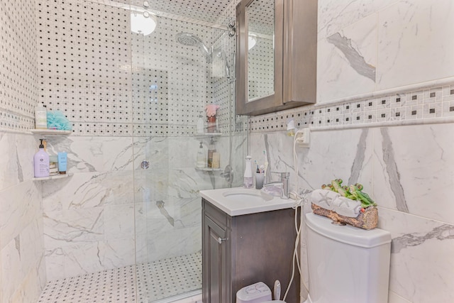 bathroom featuring vanity, toilet, a shower with shower door, and tile walls