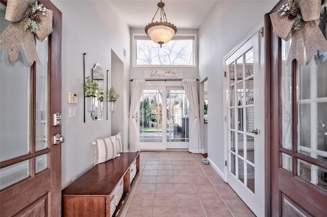 doorway featuring a towering ceiling and light tile patterned floors