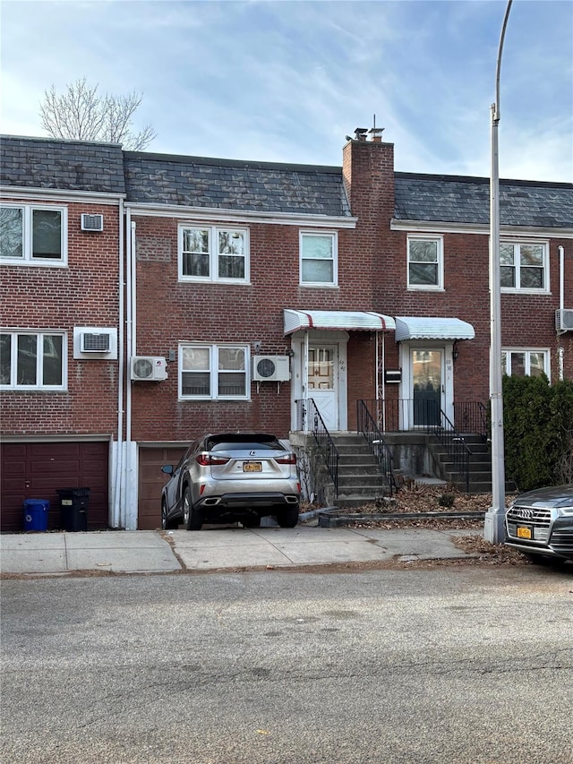 view of property with a garage and a wall unit AC