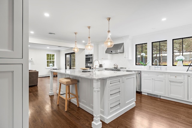 kitchen featuring pendant lighting, white cabinetry, a center island with sink, and exhaust hood