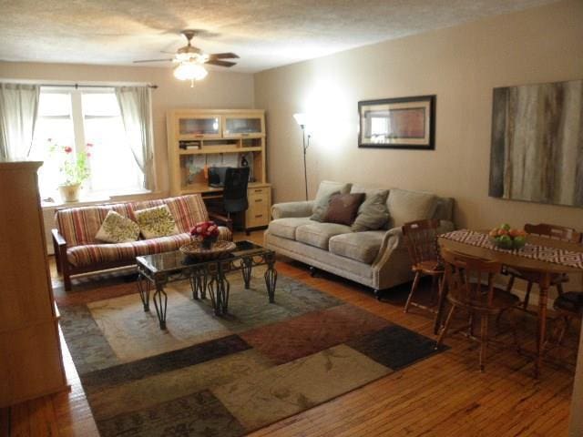 living room with ceiling fan, dark wood-type flooring, and a textured ceiling