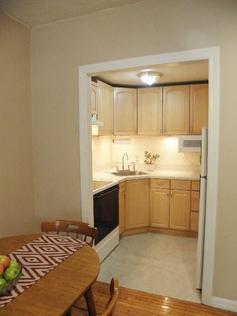 kitchen featuring light brown cabinets, exhaust hood, black range, sink, and white fridge