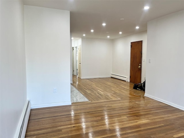 empty room featuring hardwood / wood-style floors and baseboard heating