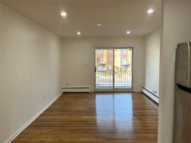 empty room with dark hardwood / wood-style flooring and a baseboard radiator