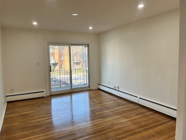 spare room with baseboard heating and dark wood-type flooring