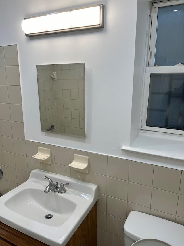 bathroom featuring vanity, toilet, and tile walls