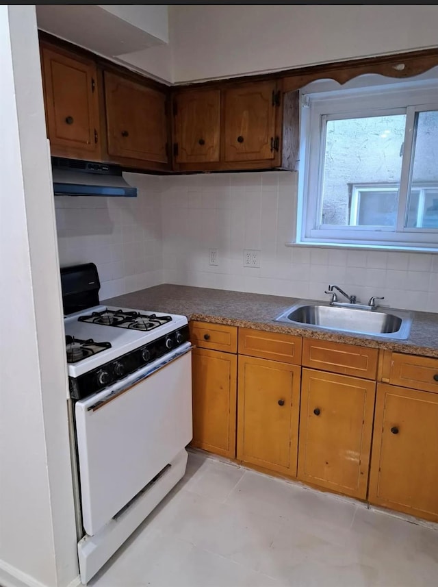 kitchen with tasteful backsplash, white range with gas cooktop, and sink