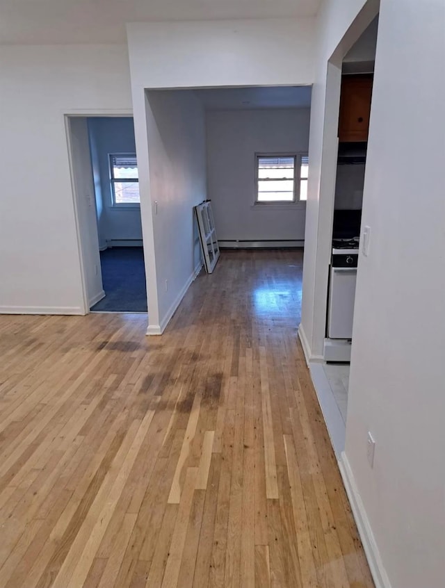 hallway featuring light wood-type flooring, a wealth of natural light, and a baseboard heating unit