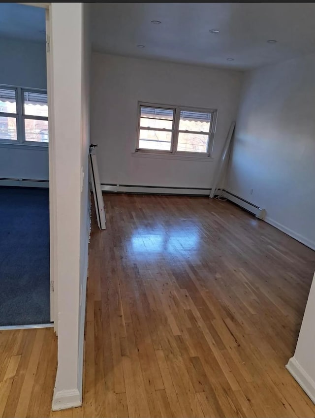 spare room featuring plenty of natural light, a baseboard heating unit, and light hardwood / wood-style flooring