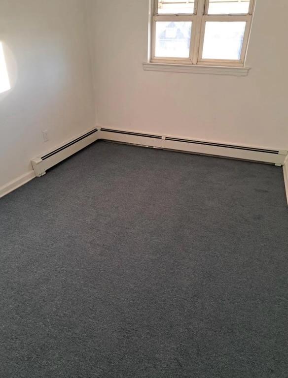 carpeted spare room with a baseboard radiator