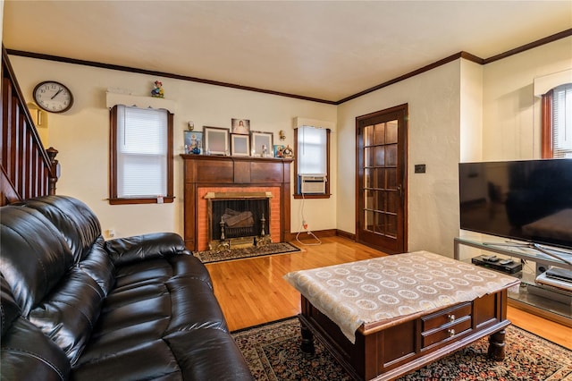 living room with light wood-type flooring, a fireplace, a wealth of natural light, and ornamental molding