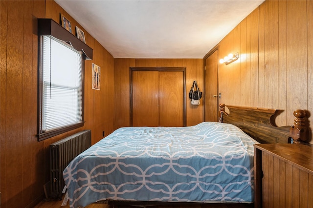 bedroom featuring wooden walls, radiator, and a closet