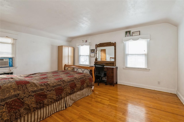 bedroom with multiple windows, light hardwood / wood-style flooring, cooling unit, and vaulted ceiling