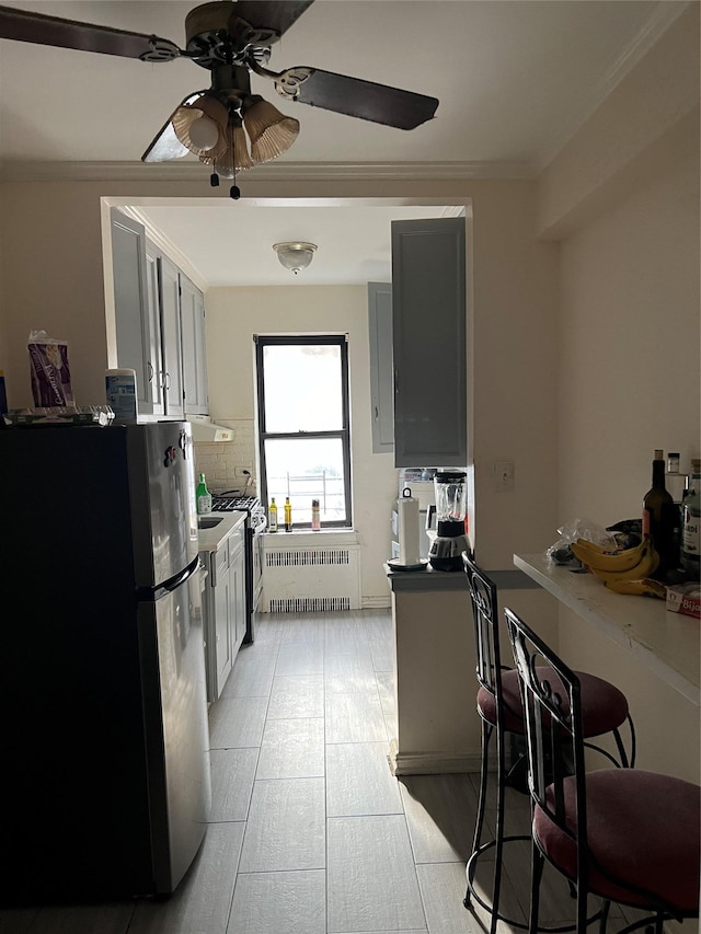 kitchen featuring radiator, gray cabinetry, ceiling fan, stainless steel fridge, and decorative backsplash