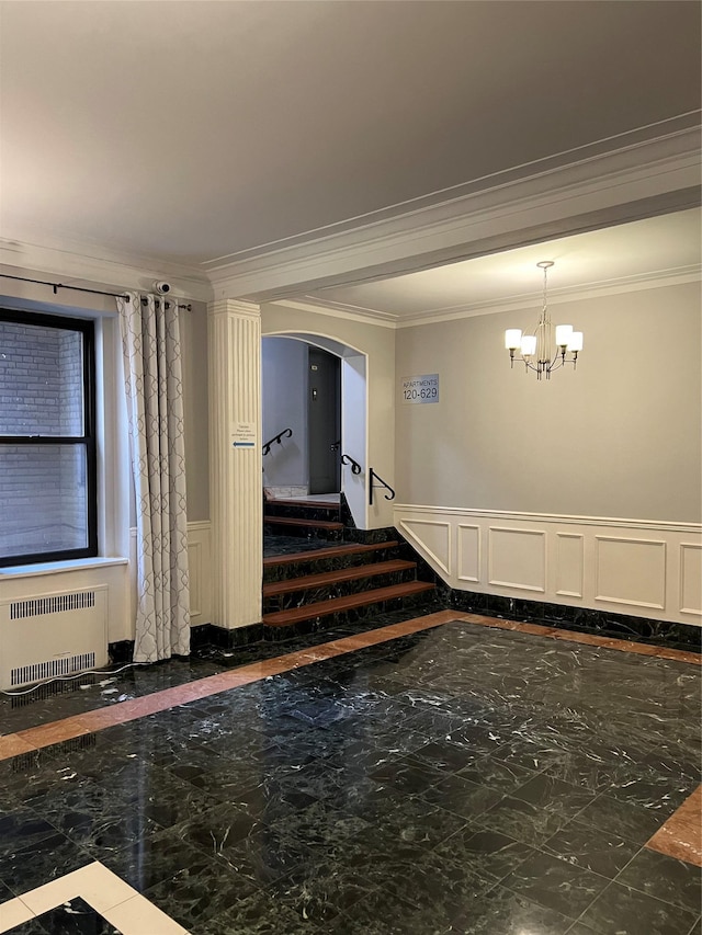 unfurnished room featuring radiator heating unit, an inviting chandelier, and ornamental molding