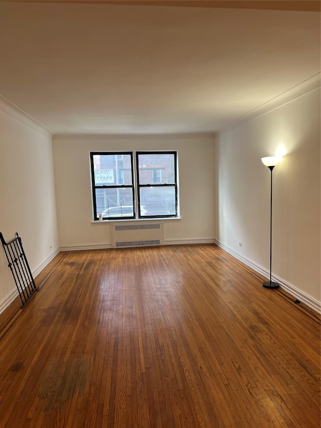 spare room with hardwood / wood-style flooring, radiator, and ornamental molding