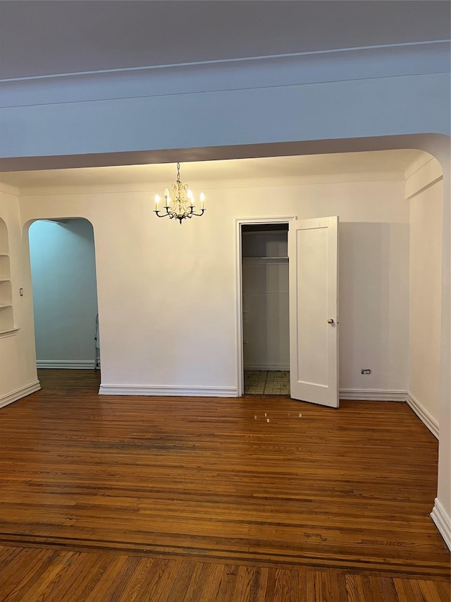 empty room featuring dark hardwood / wood-style flooring and a chandelier