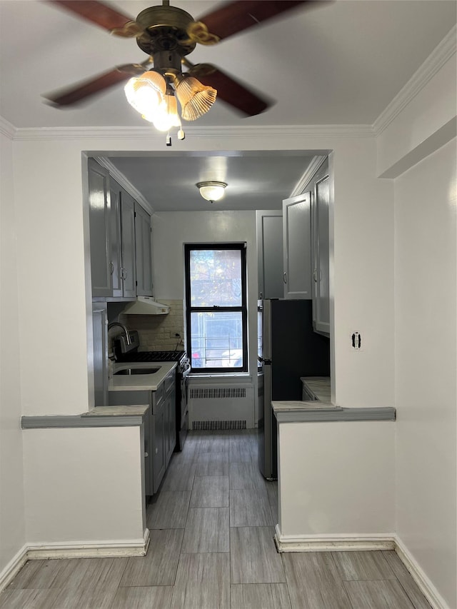 kitchen with decorative backsplash, ceiling fan, crown molding, radiator heating unit, and gray cabinets