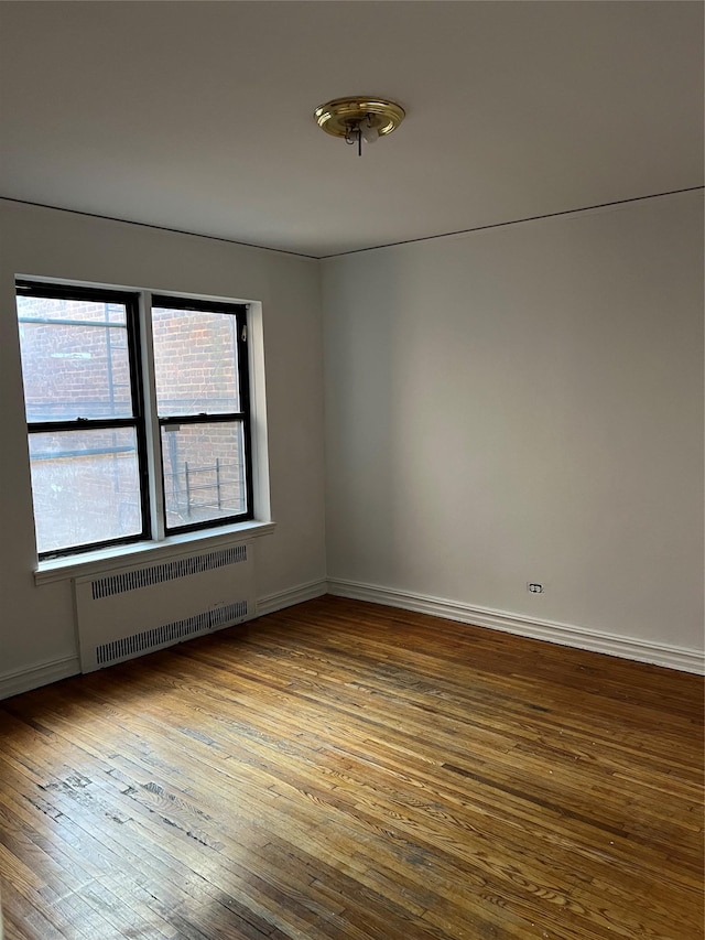 spare room with radiator heating unit and hardwood / wood-style flooring