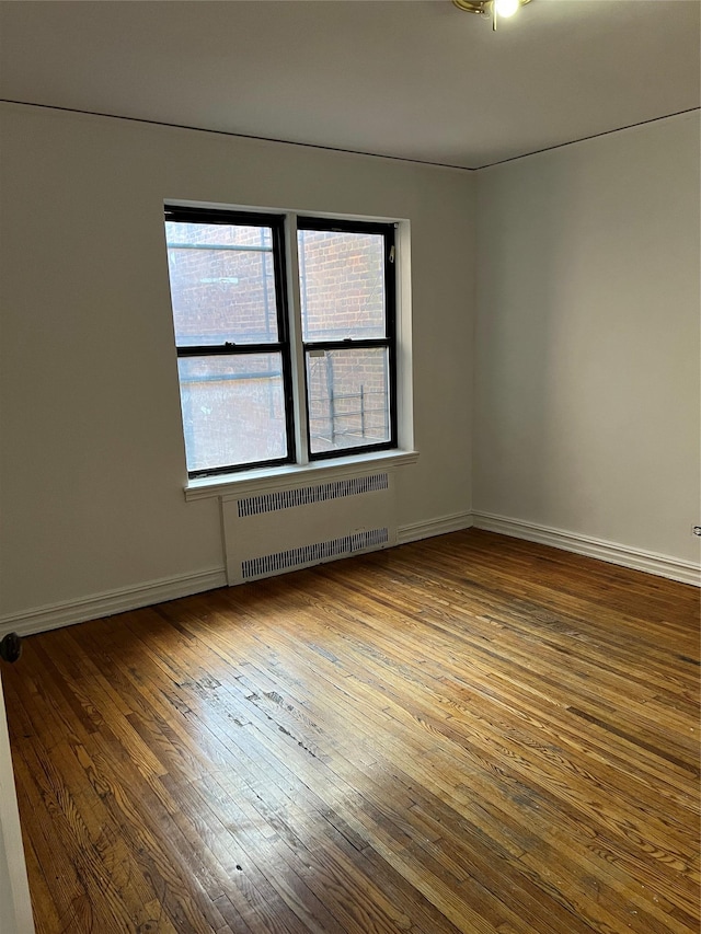 unfurnished room with radiator and wood-type flooring