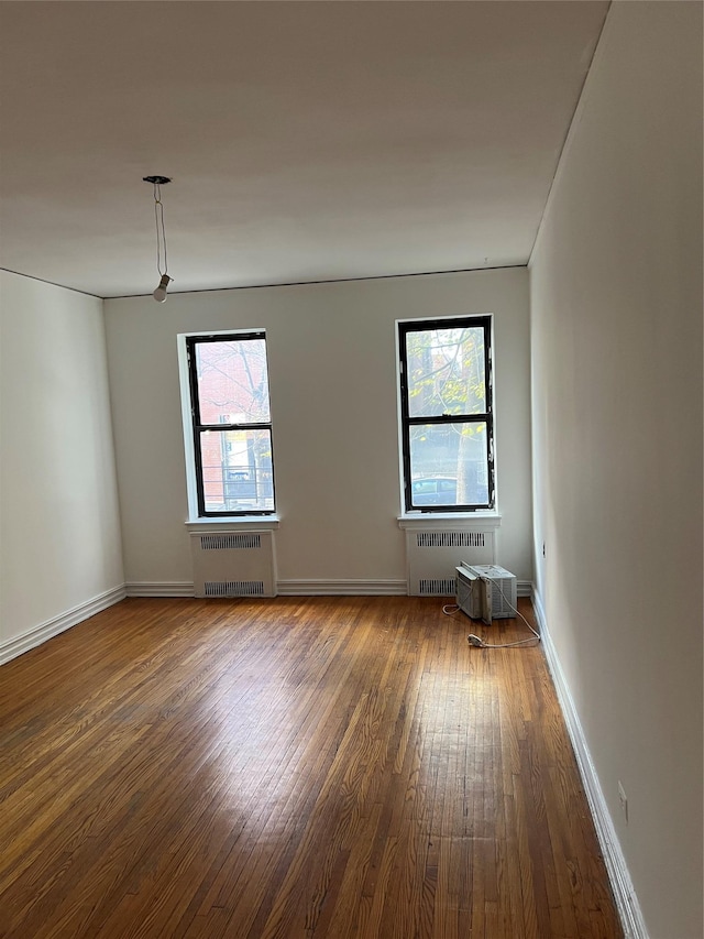 spare room featuring radiator, a wealth of natural light, and wood-type flooring