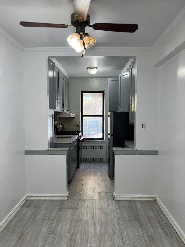 kitchen featuring gray cabinets, range hood, radiator, and tasteful backsplash