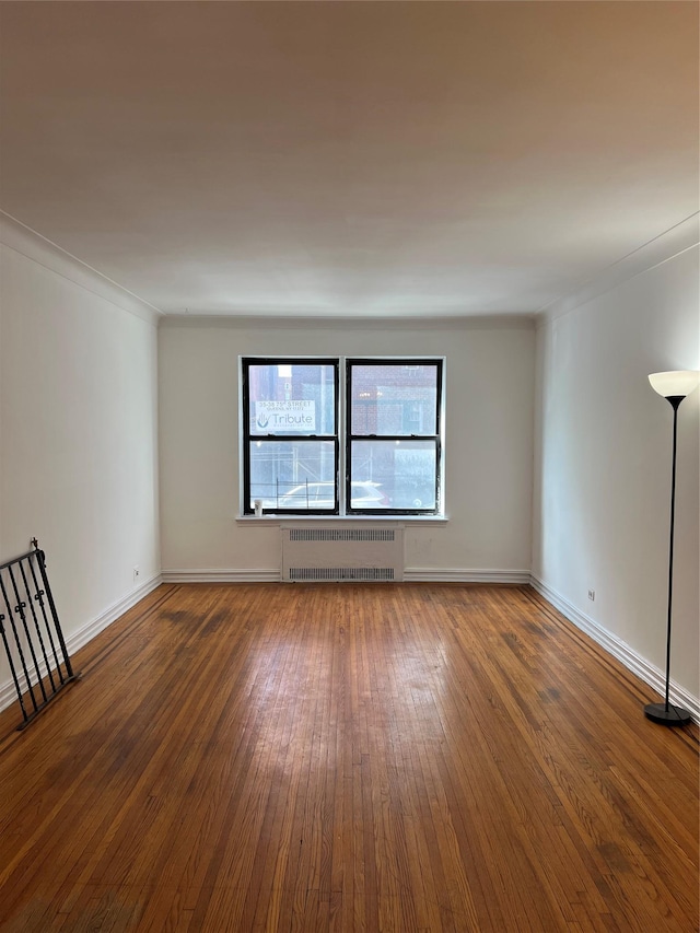 spare room with radiator, dark wood-type flooring, and ornamental molding