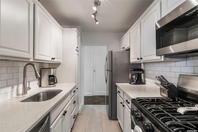 kitchen featuring decorative backsplash, white cabinetry, sink, and appliances with stainless steel finishes