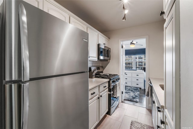 kitchen with white cabinets, light hardwood / wood-style floors, appliances with stainless steel finishes, and tasteful backsplash