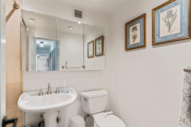 bathroom with curtained shower, sink, tile walls, and toilet