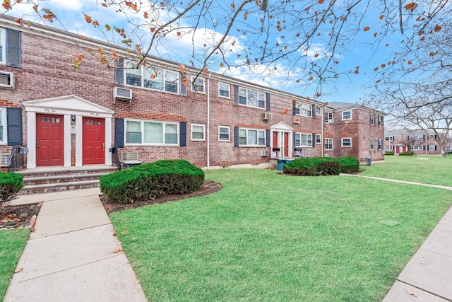 townhome / multi-family property with a wall mounted air conditioner and a front yard