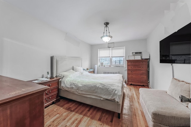 bedroom with radiator heating unit and light hardwood / wood-style floors