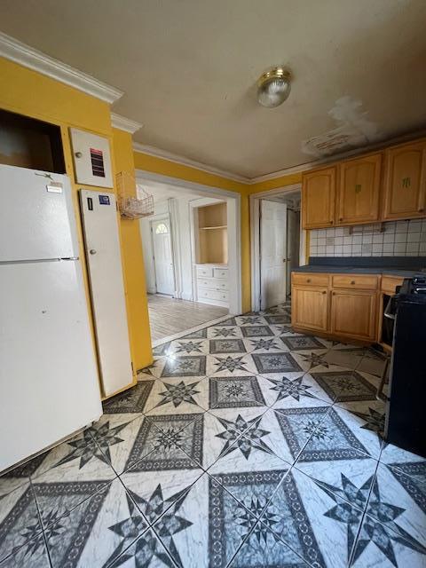 817 Southard St, Baldwin, NY 11510 - kitchen featuring freestanding refrigerator, ornamental molding, stove, dark countertops, and brown cabinetry