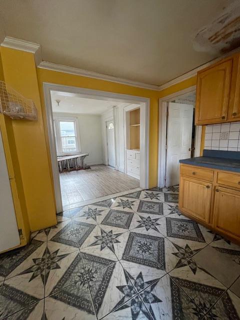 817 Southard St, Baldwin, NY 11510 - kitchen with dark countertops, crown molding, backsplash, and brown cabinetry