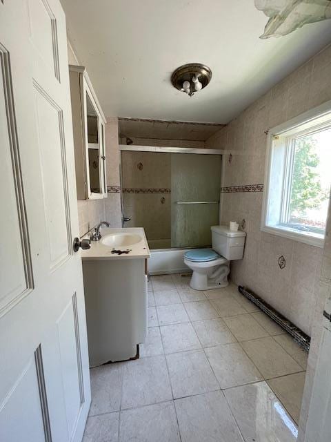 817 Southard St, Baldwin, NY 11510 - bathroom with vanity, tile patterned flooring, shower / bath combination with glass door, tile walls, and toilet