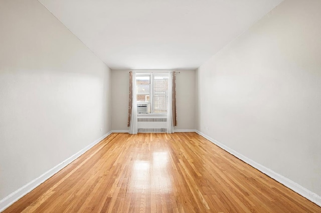 empty room with light hardwood / wood-style floors and radiator heating unit