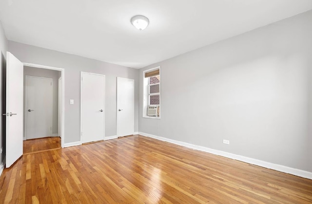 unfurnished bedroom with cooling unit and light wood-type flooring