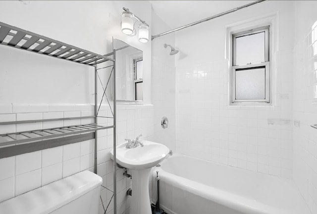 bathroom with tiled shower / bath combo, tile walls, and toilet