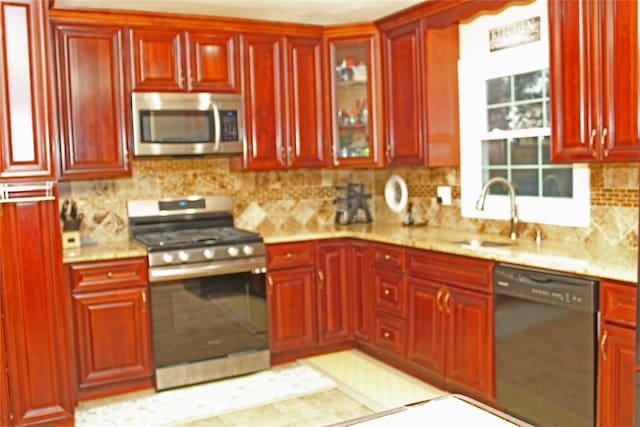 kitchen featuring backsplash, sink, light stone countertops, and stainless steel appliances