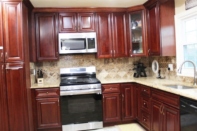 kitchen with backsplash, light stone countertops, sink, and appliances with stainless steel finishes