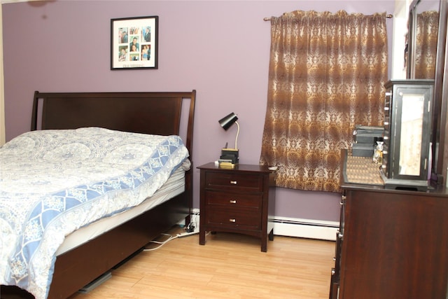 bedroom featuring a baseboard heating unit and light hardwood / wood-style flooring