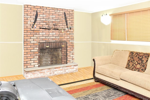 living room with a brick fireplace and hardwood / wood-style flooring