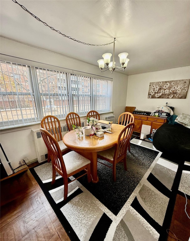 dining area with dark parquet floors and a chandelier